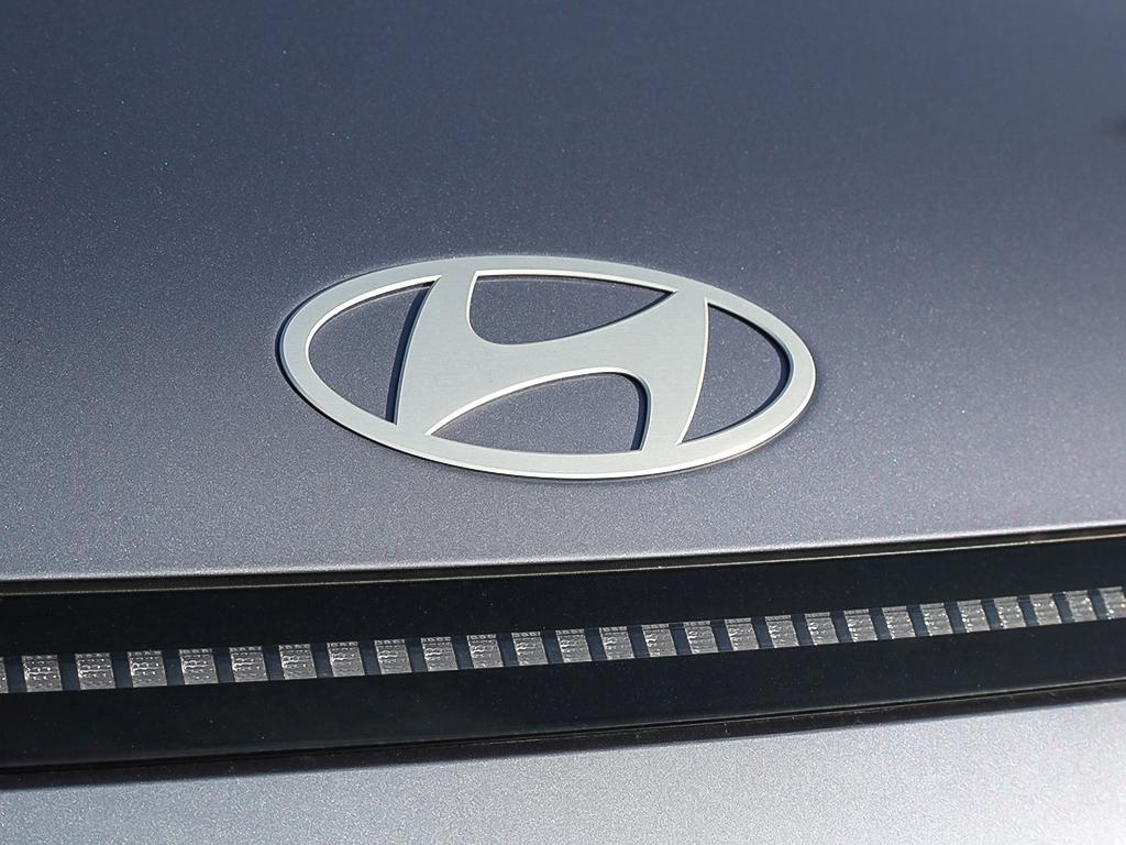 Kona EV Ultimate 2026 Extérieur, vue en gros plan du logo Hyundai à l'avant, discrètement intégré au-dessus de la ligne des phares.