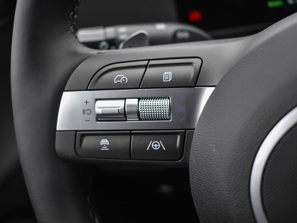 Kona EV Ultimate 2026 Intérieur, gros plan sur les commandes gauches sur le volant. On voit les boutons d'aide à la conduite.