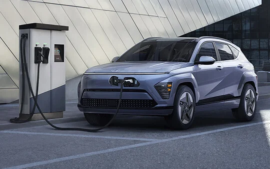 Side exterior view of Hyundai KONA Electric while charging Visual example only. Canadian charging infrastructure may appear differently.